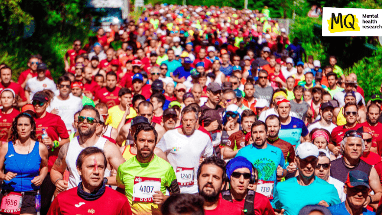 Marathon runners in bright colours run towards the camera in a sea of people