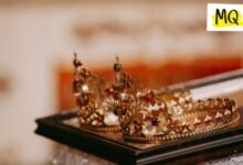 Two gold tiara style crowns lie on a wooden tray at a tiled angle of approximately 45 degree sloping downwards