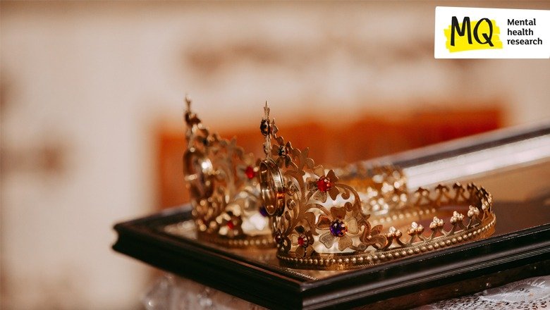 Two gold tiara style crowns lie on a wooden tray at a tiled angle of approximately 45 degree sloping downwards