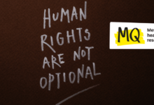 On a black slate surface, the words 'Human rights are not optional' are written in chalk, in capitals and underlined.